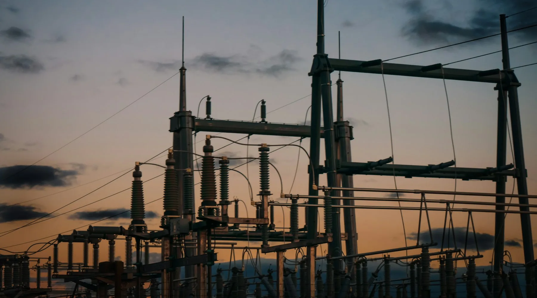 Electrical substation equipment silhouetted against a sunset sky.